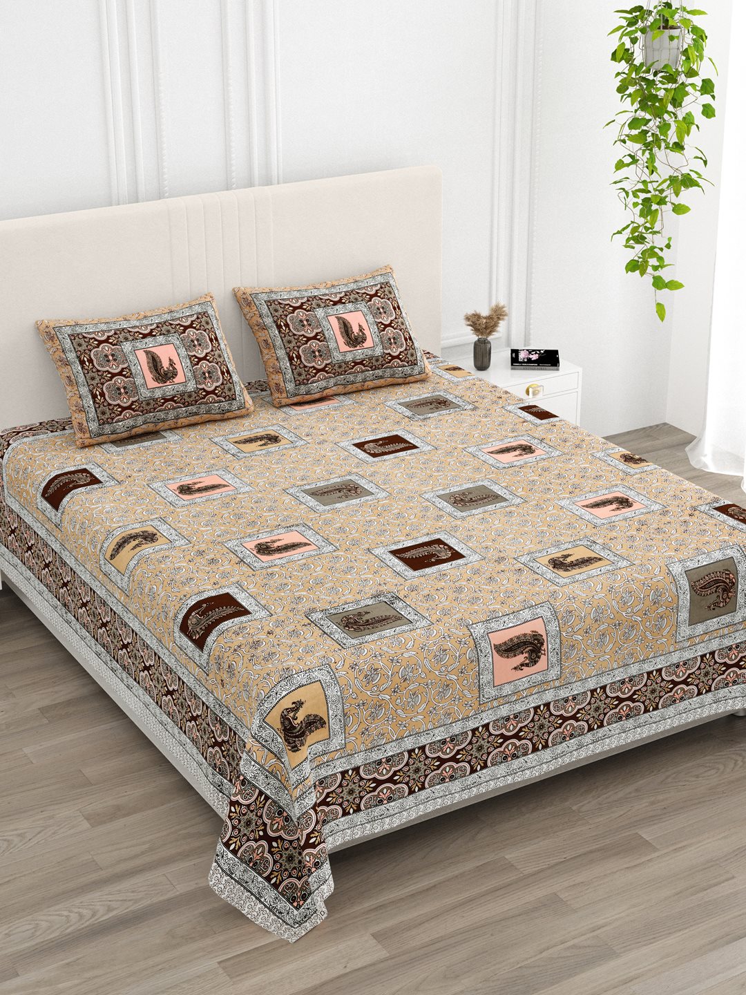 Angled view of the beige peacock print bedsheet in a bright bedroom with an indoor plant