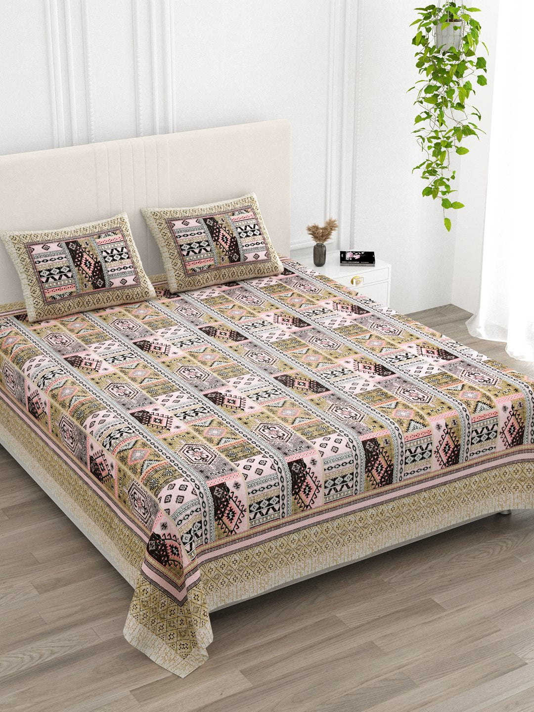 Angled view of the beige & pink Aztec patchwork bedsheet on a bed with 2 pillow covers