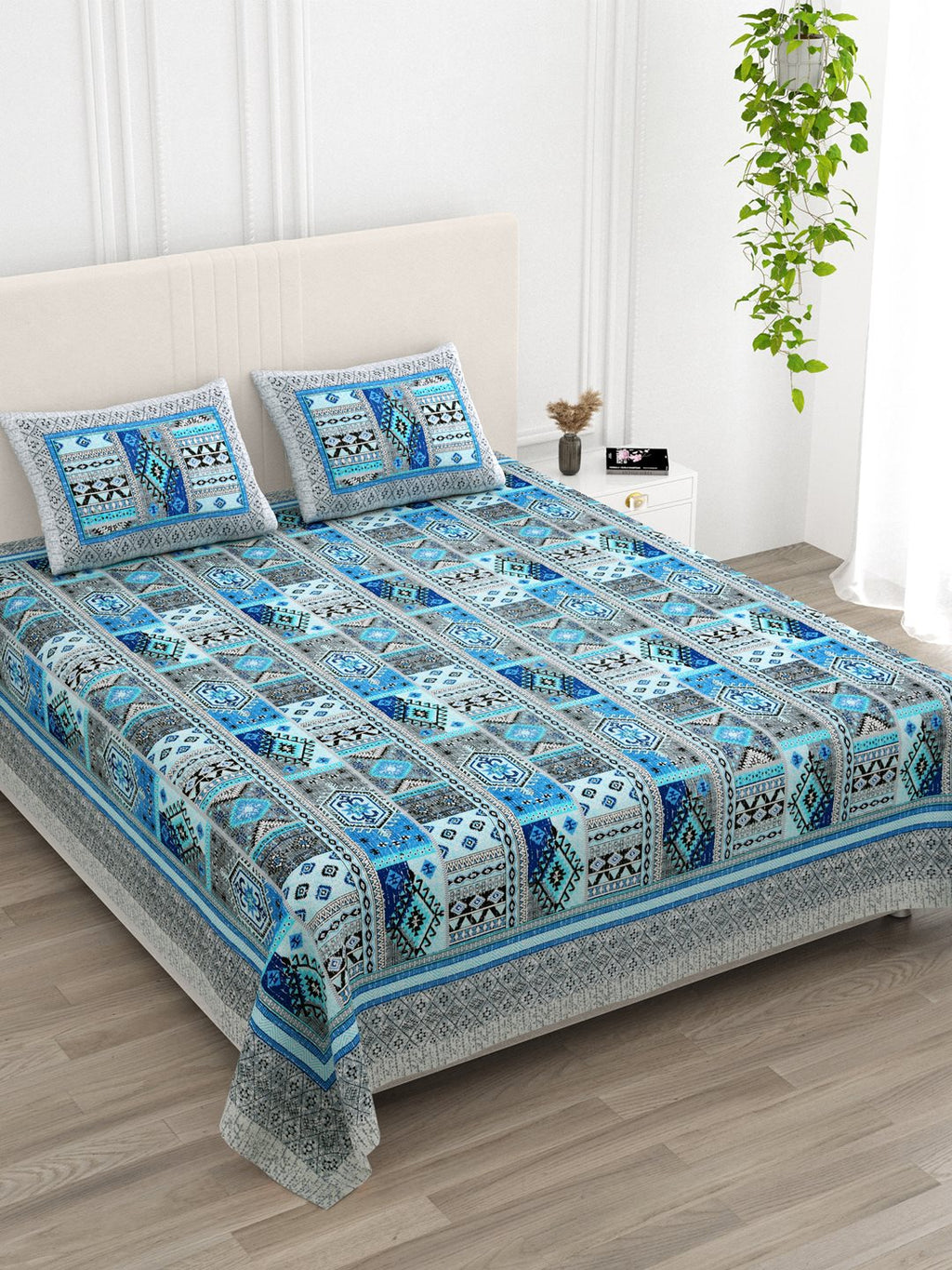 Angled view of the blue & grey Aztec patchwork bedsheet on a bed with 2 pillow covers