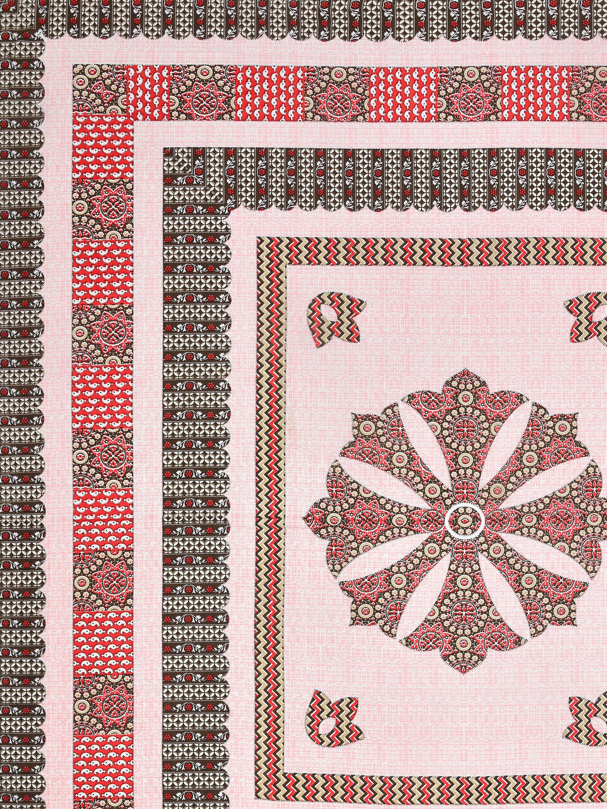 Flat corner close-up of the pink medallion bedsheet showing brown borders and red panel band