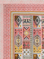 Corner close-up of mustard yellow, brown, grey and black kilim-style panels and the coral pink geometric border