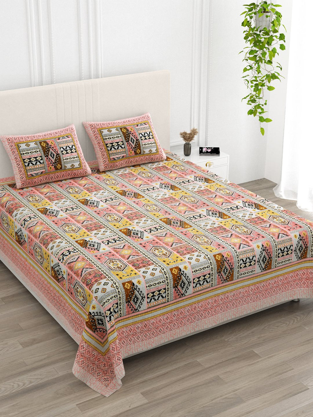 Angled view of the coral & mustard Aztec patchwork bedsheet on a bed with 2 pillow covers