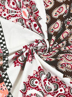 Swirled fabric close-up of maroon and brown paisley print on white