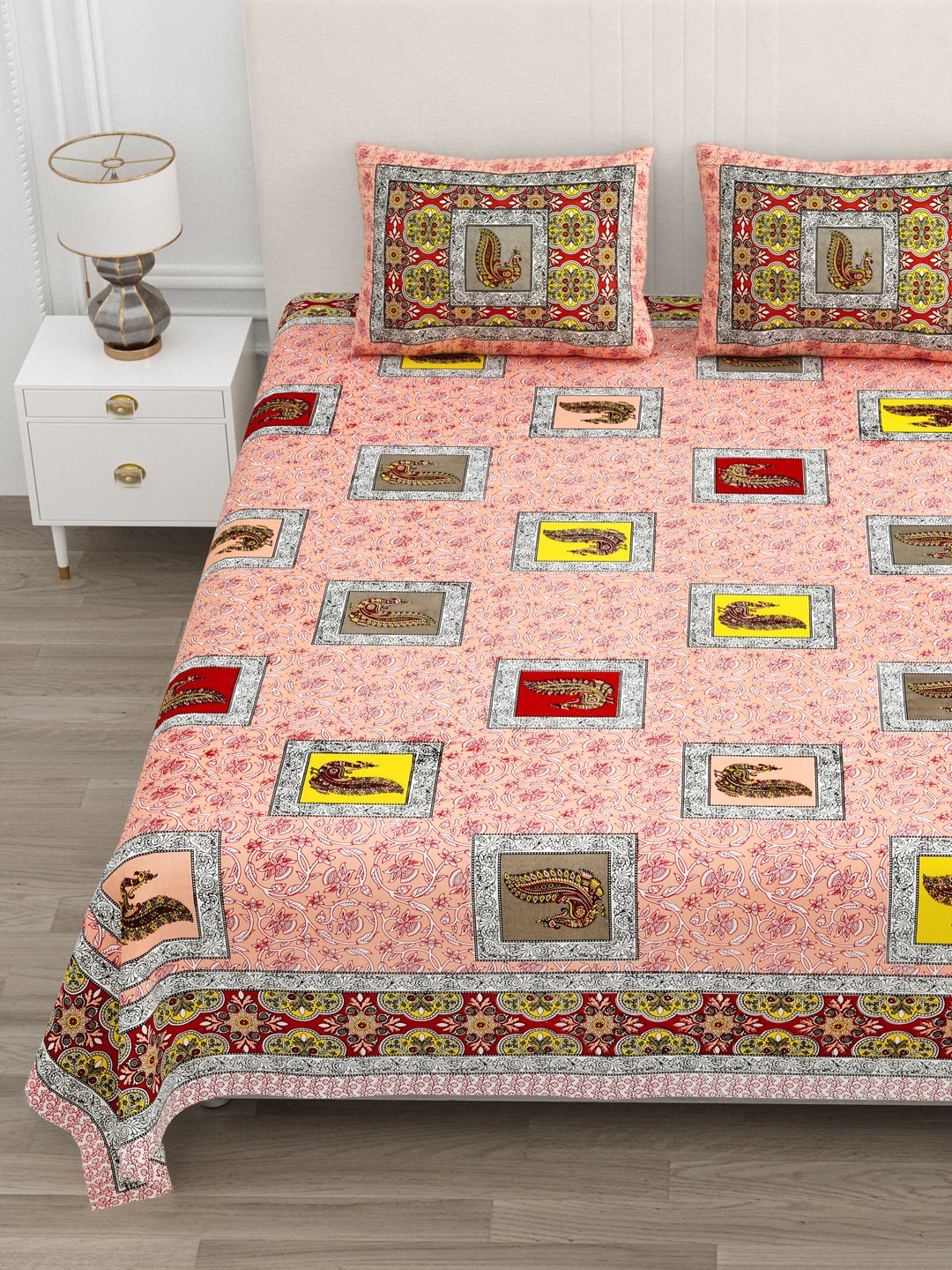 Close view of peacock patches and the ornamental border on the peach bedsheet