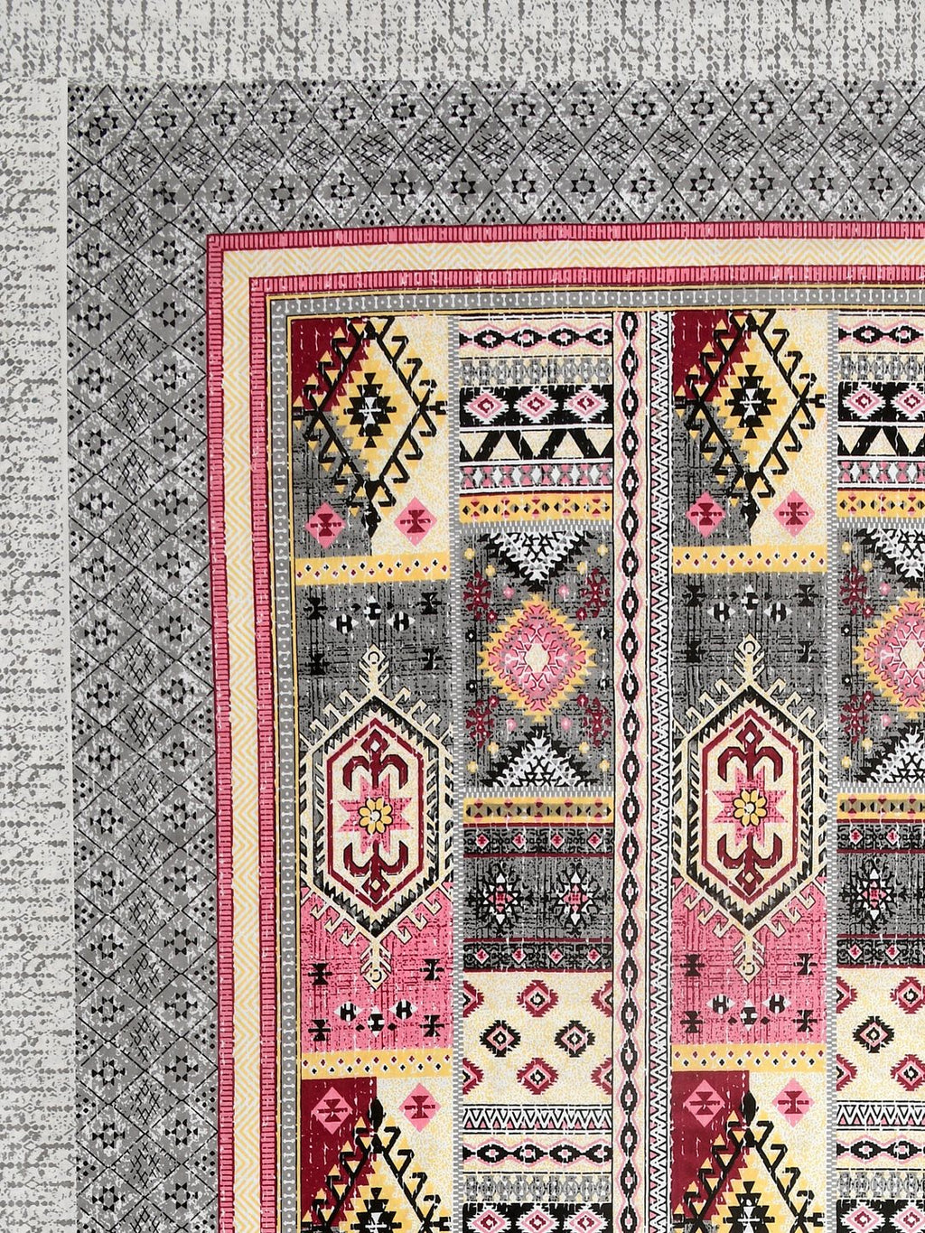 Corner close-up of rose pink, maroon, butter yellow and black kilim-style panels and the grey geometric border