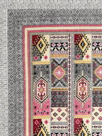 Corner close-up of rose pink, maroon, butter yellow and black kilim-style panels and the grey geometric border