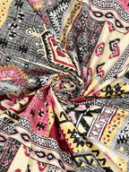 Swirled fabric close-up of pink & grey Aztec and kilim-style geometric print