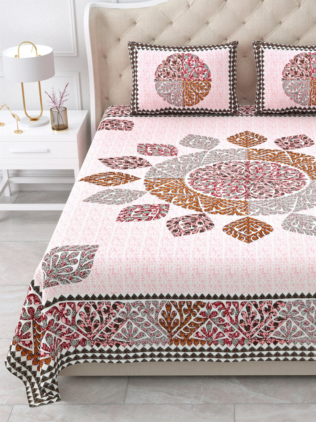 Close view of the maroon, caramel and grey leaf mandala and border on the pink bedsheet