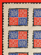 Flat corner view of the cream bedsheet with red and blue square blocks and a solid red border