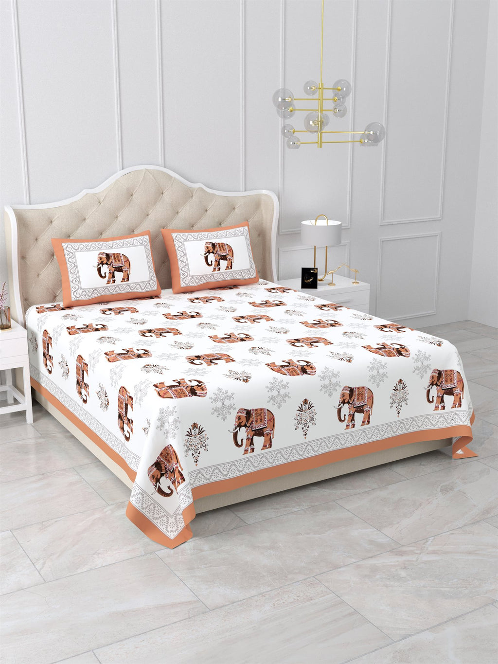 Angled view of the rust orange elephant print bedsheet on a bed with 2 pillow covers