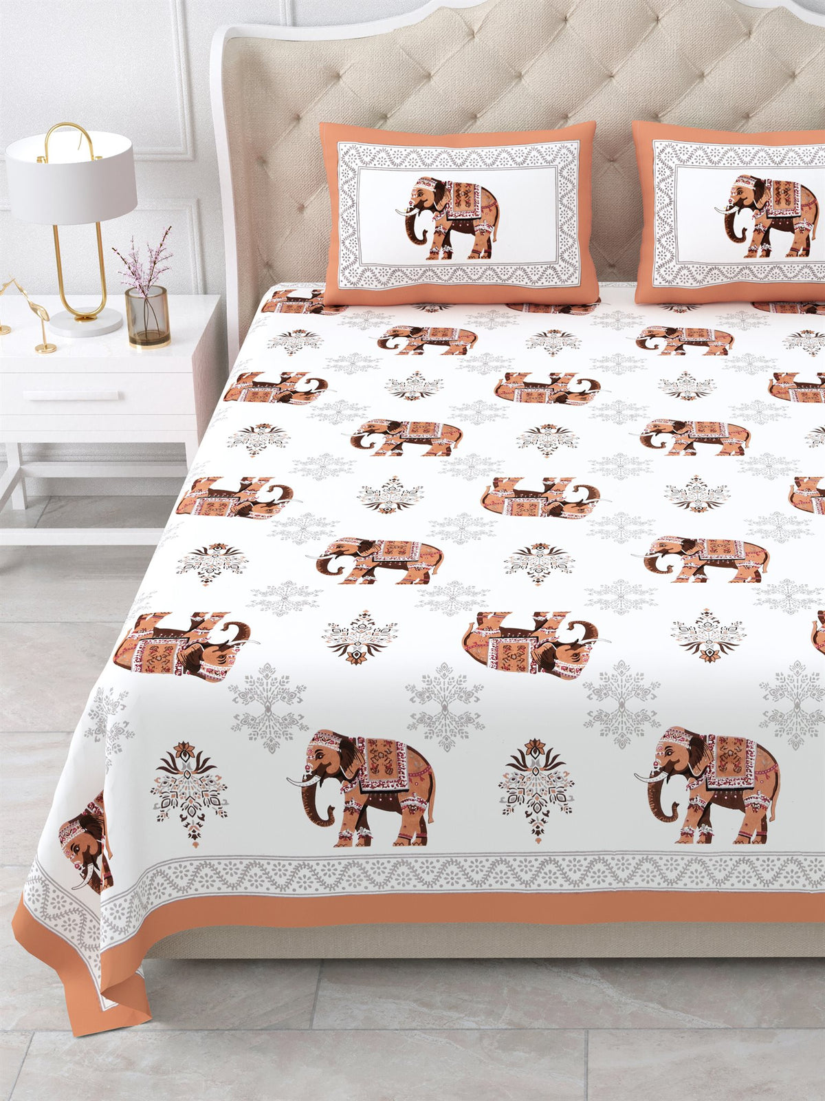 Close front view of the rust orange elephant print bedsheet and framed pillow covers