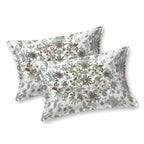 Two white pillow covers with sage-grey leaves and an oval cluster of olive and charcoal flowers