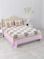 Angled view of the beige buta print bedsheet with a wide soft pink border along the side