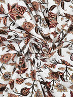 Swirled fabric close-up of rust, peach and brown floral vines on a white base
